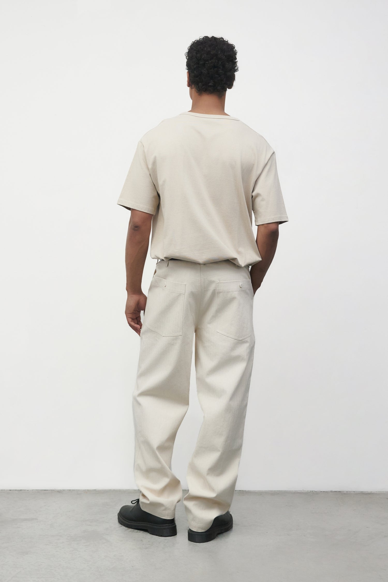 Model wearing bone elias top with cream pants and black oxfords, back view