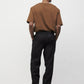 Model wearing brown elias top with black trousers and black boots, back view