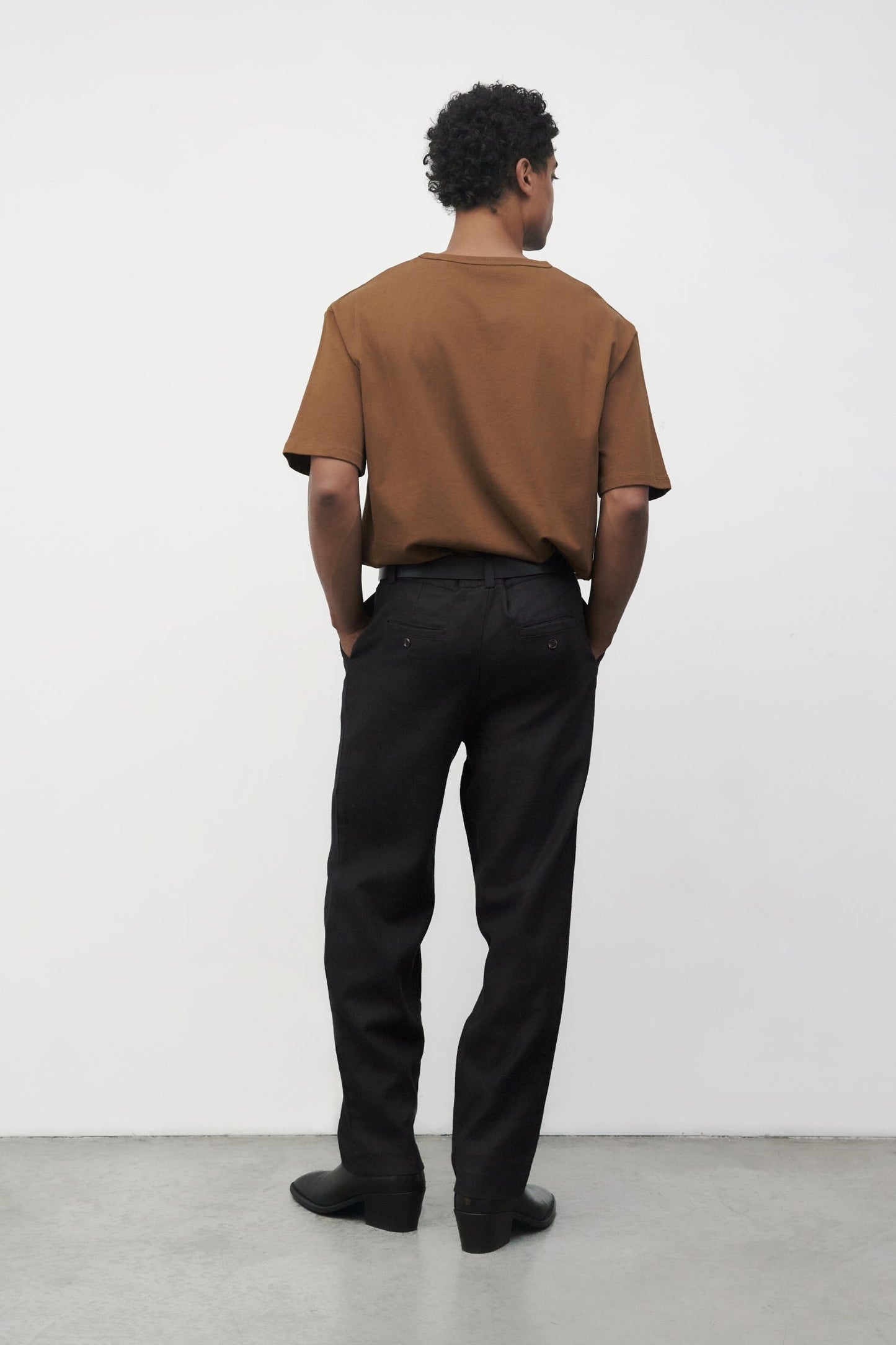 Model wearing brown elias top with black trousers and black boots, back view