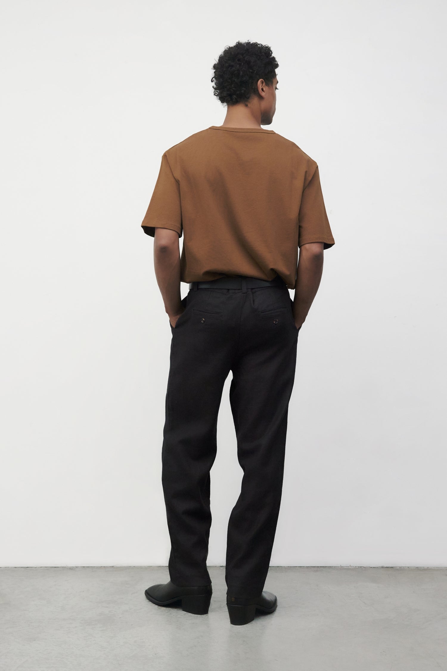 Model wearing brown elias top with black trousers and black boots, back view
