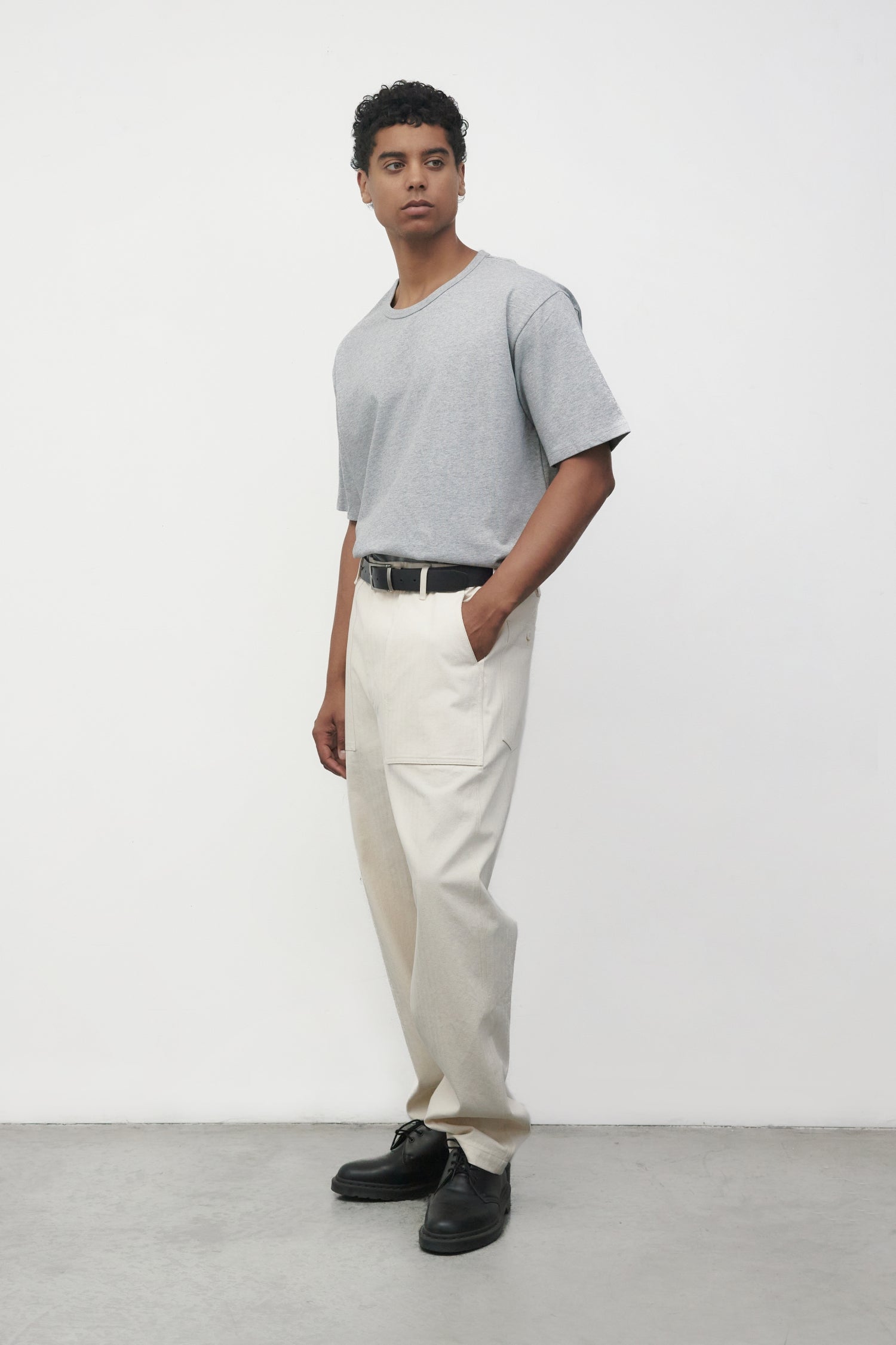 Model wearing heather grey elias top with cream pants, side view