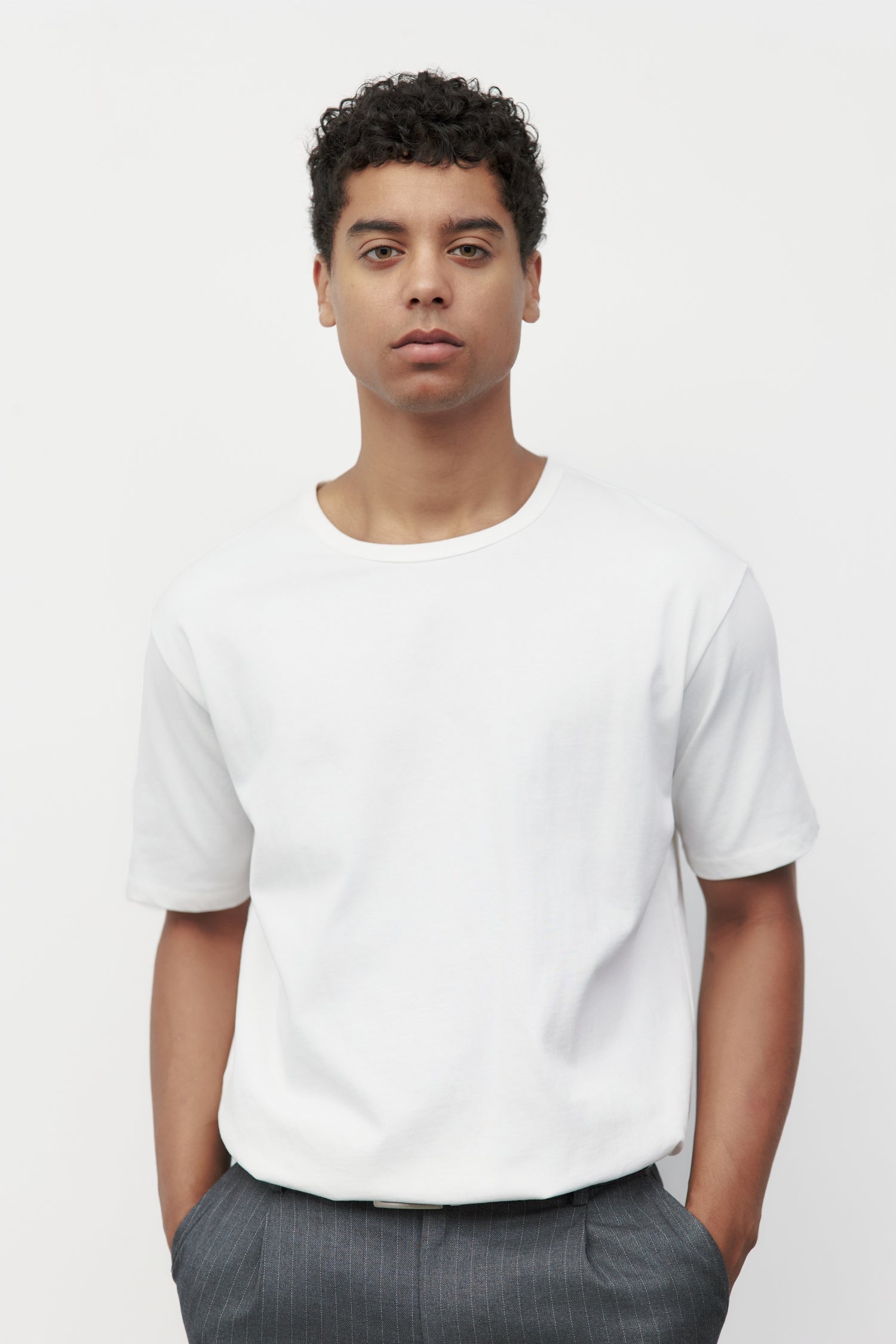 Model wearing white elias top with trousers and black loafers, close up