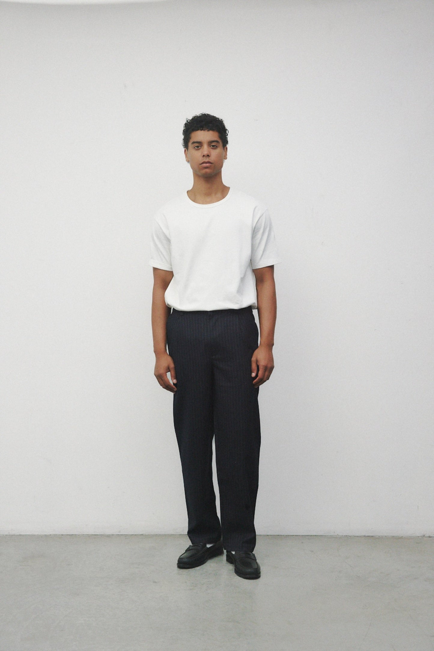 Model wearing white elias top with trousers and black loafers