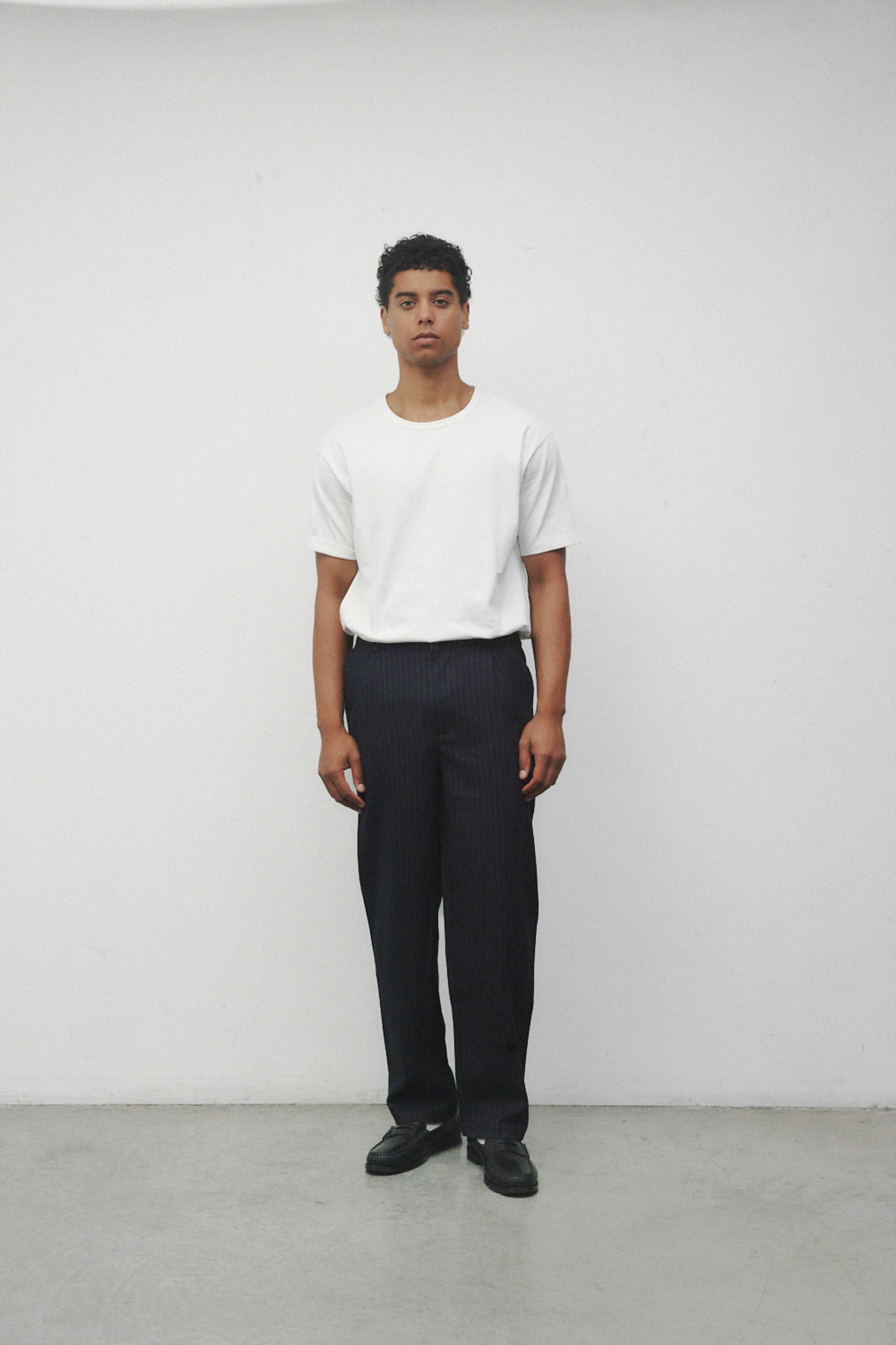 Model wearing white elias top with trousers and black loafers